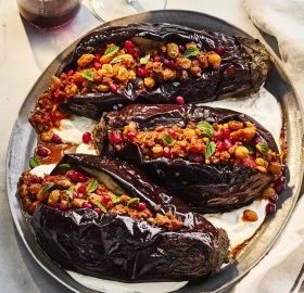 Gefüllte Auberginen mit einer Mischung aus Nüssen, Hackfleisch und Kräutern auf einer Servierplatte.